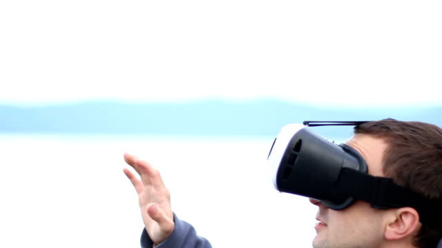 man-uses-a-virtual-reality-glasses-against-the-sky-and-landscape