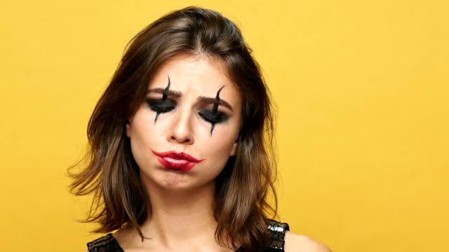 Verärgert-Brünette-Lady-mit-gruseligen-make-up-für-Halloween-suchen-Kamera-über-gelb-isoliert