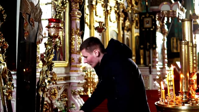 Der-junge-Mann-beugt-und-küsst-das-Kreuz-in-der-orthodoxen-Kirche