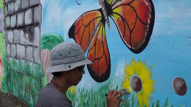Mural-painter-paints-butterfly-in-color-on-school-wall.