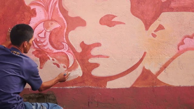Mural-painter-draws-a-human-face-image-on-school-wall.