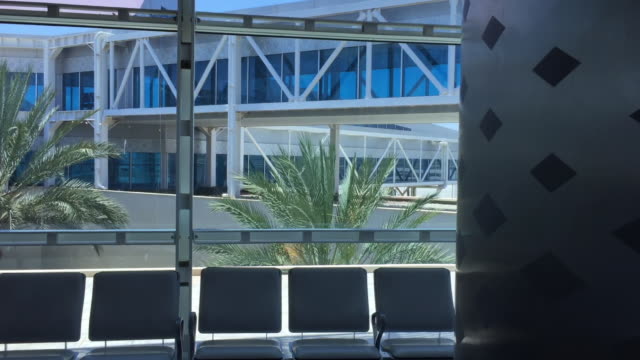 Panoramic-window-with-view-on-palm-trees-and-gates-to-aircraft-in-airport.-Airport-background-with-window-view