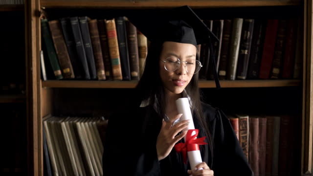 Happy-asian-student-in-round-glasses-and-black-gown-enjoying
