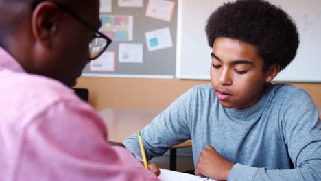 High-School-Tutor-Giving-Male-Student-One-To-One-Tuition-At-Desk