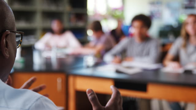 Pull-Focus-Shot-Of-Male-High-School-Tutor-Teaching-Students-In-Biology-Class