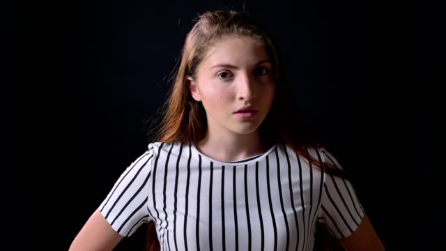 Occupied-young-woman-in-striped-shirt-looking-at-camera-and-standing-isolated-on-black-background