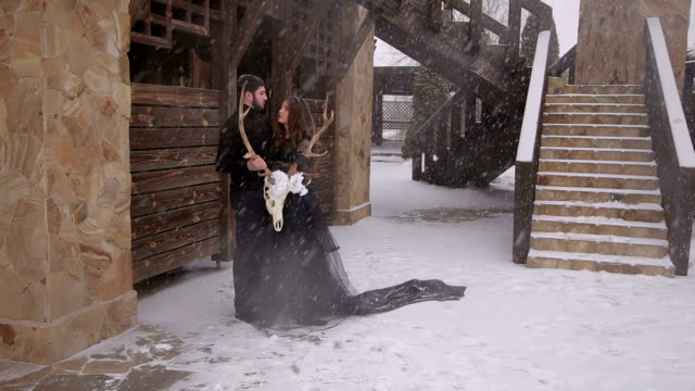 A-loving-couple-in-black-clothes-under-a-snowfall.