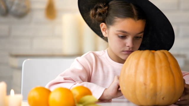 Pretty-little-girl-making-jack-pumpkin-and-preparing-for-Halloween-eve-party