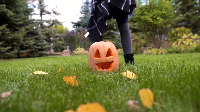 Happy-girl-taking-pumpkin-Jack-in-hands,-playing-in-yard,-Halloween-celebration