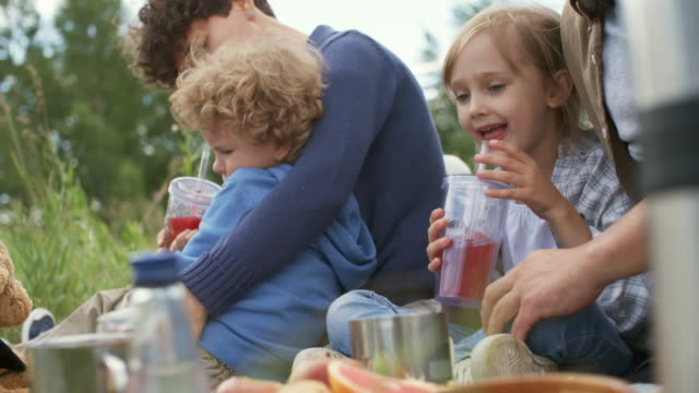 Kinder-trinken-Saft-auf-Picknick-mit-Eltern