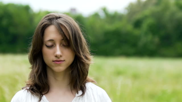 Young-woman-in-simple-dress-meditates-outdoors,-green-fields,-inner-temple-God