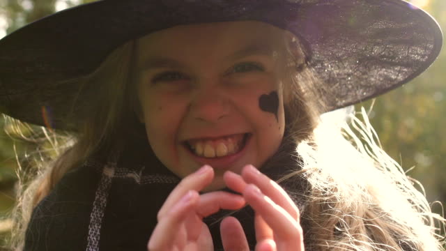 Little-witch-making-scary-face-to-camera-having-fun-at-Halloween-party-happiness