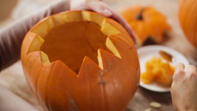 close-up-of-woman-carving-halloween-pumpkin