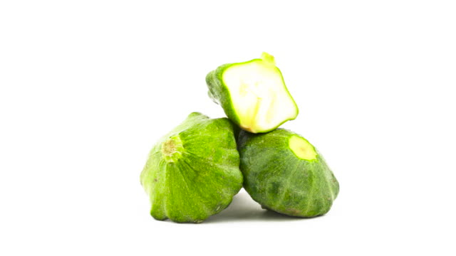 Two-whole-green-pattypan-squashes-and-one-half-cut-patty-pan-squash.-Rotating.-Isolated-on-the-white-background.-Close-up.-Macro.
