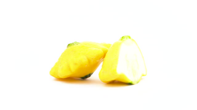 One-whole-and-one-half-of-yellow-patisson-squashes-with-water-drops.-Rotating-on-the-turntable.-Isolated-on-the-white-background.-Close-up.-Macro.
