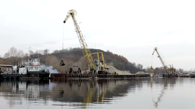 The-industrial-port-pour-sand-on-the-barge-with-a-crane