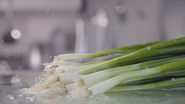 Falling-of-leek-green-onion-into-the-wet-table.-Slow-motion-240-fps