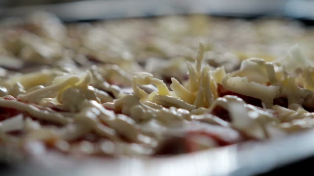 Cheese-falls-on-the-sauce-and-salami-delicious-and-appetizing-pizza,-close-up.-The-concept-of-pizza