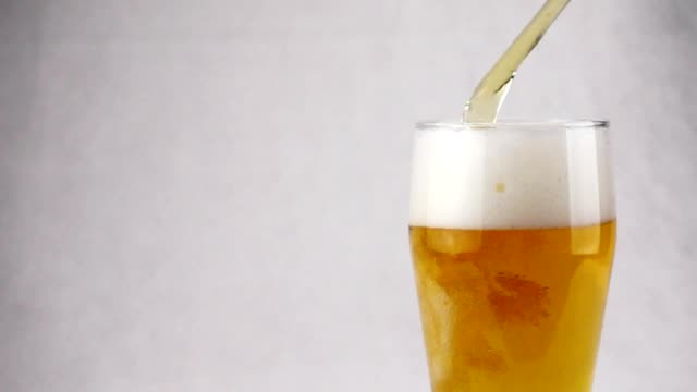 Cerveza-de-cerveza-dorada-ligera-está-vertiendo-en-vidrio-sobre-fondo-blanco.-Cámara-lenta