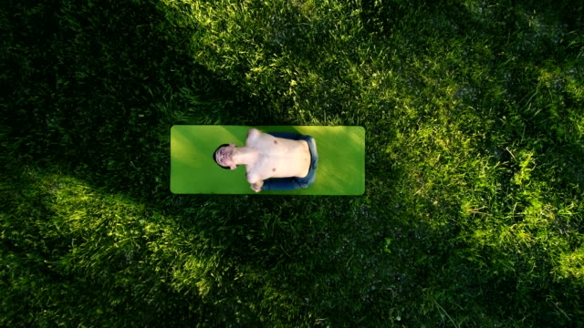 Young-man-practicing-yoga-in-park.
