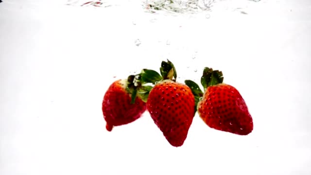Die-rote-Erdbeere-fällt-wunderschön-mit-Luftblasen-ins-Wasser.-Video-Beryy-auf-isolierte-Hintergrund-in-Zeitlupe.