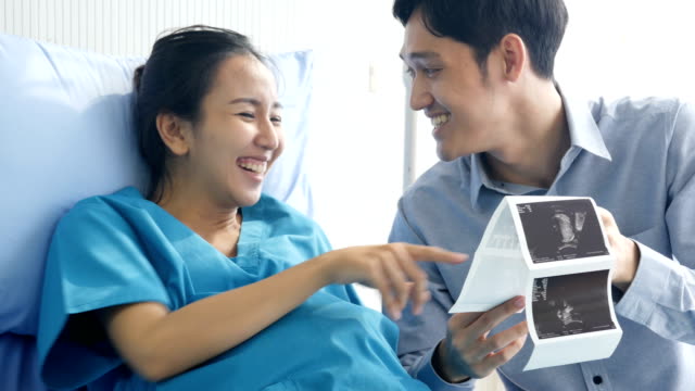 Pregnant-woman-and-husband-looking-to-x-ray-film-with-happy-emotion-together.-People-with-healthcare-and-medical-concept.
