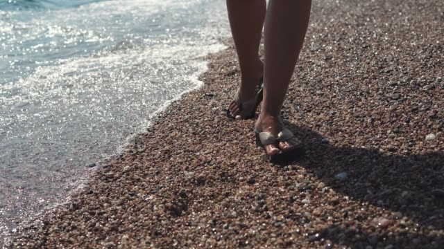 Woman's-legs-in-flip-flops-on-beach.