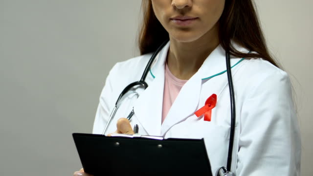Therapist-with-red-ribbon-prescribing-medication,-fight-against-AIDS-epidemic