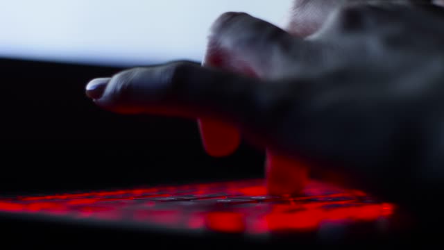 mano-de-la-chica-hacker-escribiendo-en-el-teclado-con-retroiluminación-roja