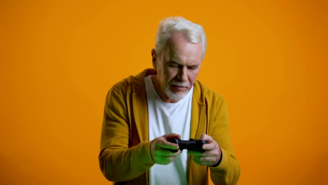 Emotional-senior-man-with-joystick-playing-videogame,-upset-with-round-result