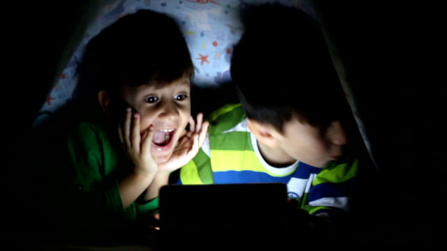 Kleiner-Junge-lesen-Buch-auf-digitalen-Tablet-in-der-Nacht