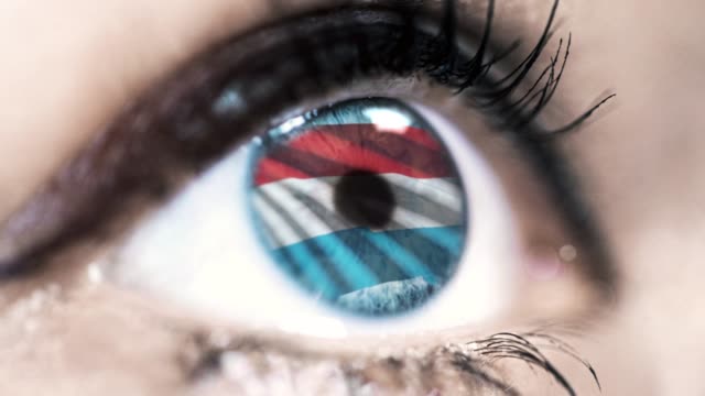 Frau-blaues-Auge-in-Nahaufnahme-mit-der-Flagge-von-Luxemburg-in-Iris-mit-Windbewegung.-Videokonzept