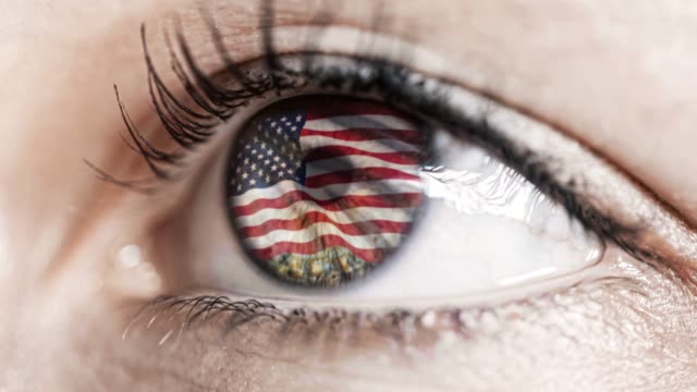 Frau-grünes-Auge-in-Nahaufnahme-mit-der-Flagge-der-USA-in-Iris-mit-Windbewegung.-Videokonzept