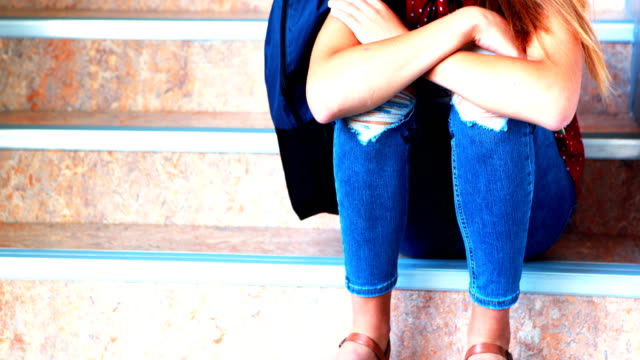 Traurig-Schülerin-sitzt-alleine-auf-Treppe