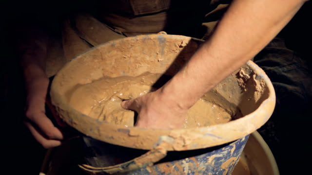 A-man-potter-starts-mixing-clay-in-a-bucket.