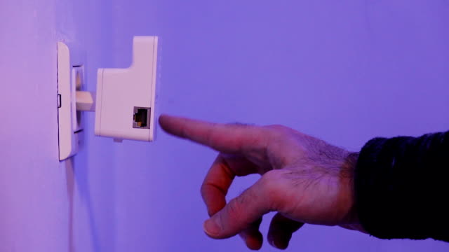 Hombre-Presione-con-su-dedo-sobre-el-botón-WPS-WiFi-repetidor-que-se-encuentra-en-el-enchufe-en-la-pared