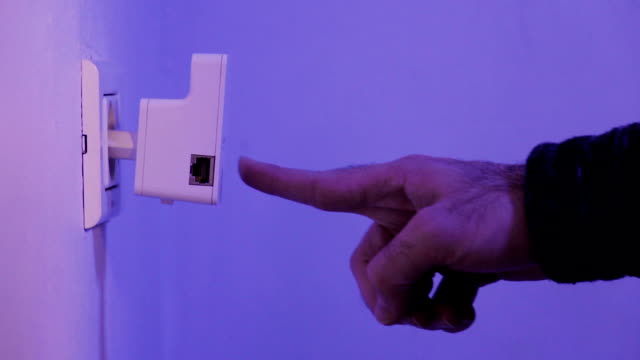 Hombre-Presione-con-su-dedo-sobre-el-botón-WPS-WiFi-repetidor-que-se-encuentra-en-el-enchufe-en-la-pared