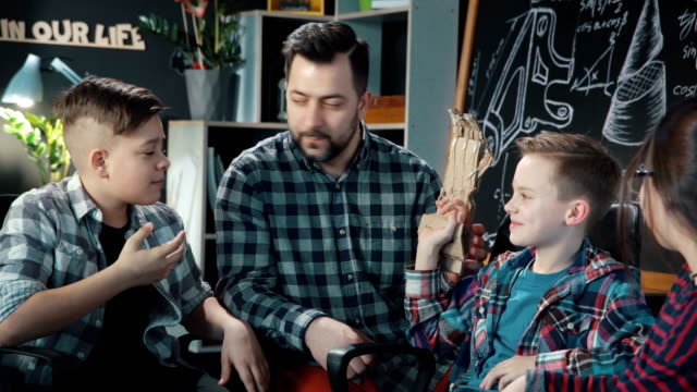 Hombre-con-hijos-explorando-cartboard-mecánico-mano