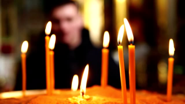Ein-Mann-aus-der-Ferne-betrachtet-brennenden-Kerzen-in-eine-Kerze-in-einem-Christian-Church