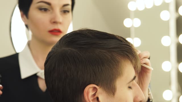 Frau-Friseur-Haarausfall-mit-Kamm-Kämmen-und-Beregnung-Wasser-vor-dem-Haircuting-im-Beauty-Salon.-Friseur-arbeitet-in-Friseur