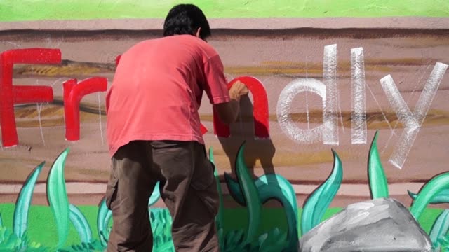 Mural-painter-draws-letter-n-on-school-wall