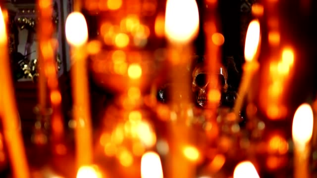Cráneo-en-foco,-en-el-primero-plano-velas-encendidas-en-la-iglesia-ortodoxa-cristiana