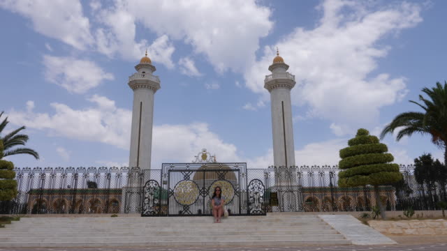 Touristischen-junge-Frau-sitzt-auf-der-Treppe-in-der-Nähe-von-Tor-im-Mausoleum-Habib-Bourguiba-in-Tunesien