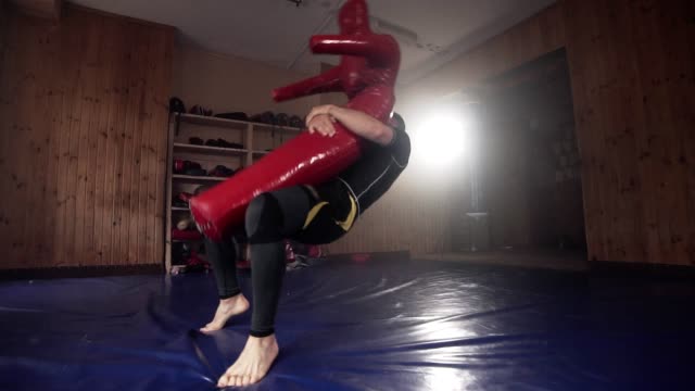 Luchador-golpea-maniquí-saco-de-boxeo-en-gimnasio-durante-la-práctica-de-la-técnica-del-combate