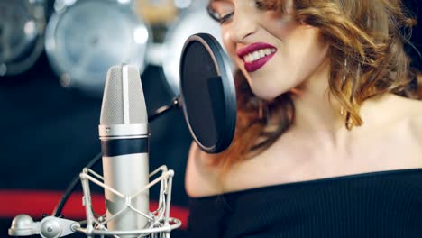 una-mujer-talentosa-con-maquillaje-brillante-es-cantando-en-un-micrófono-en-un-estudio-de-grabación-de-audio.