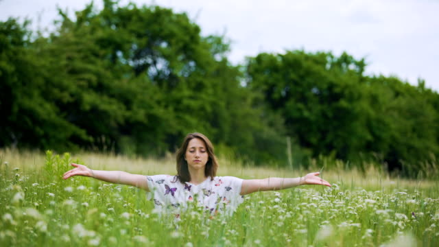 Mujer-joven-en-hierba-verde-haciendo-práctica-budista,-namaste-después-de-la-meditación