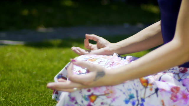 Hands-in-gyan-mudra-rack-focus,-woman-sits-in-park-and-meditates,-proper-pose