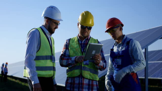 Tres-trabajadores-de-la-electricidad-revisar-documentos-en-forma-de-tabletas