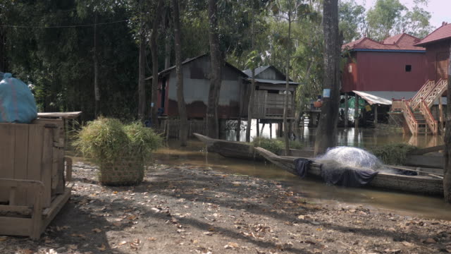 Flood-waters-under-stilt-houses-with-small-dugout-canoes-in-courtyard.