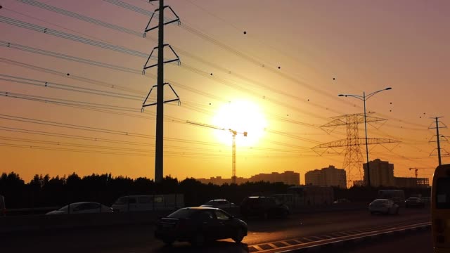 Traffic-jam-on-the-highway-at-an-orange-sunset---electricity-pole-(transition-tower)